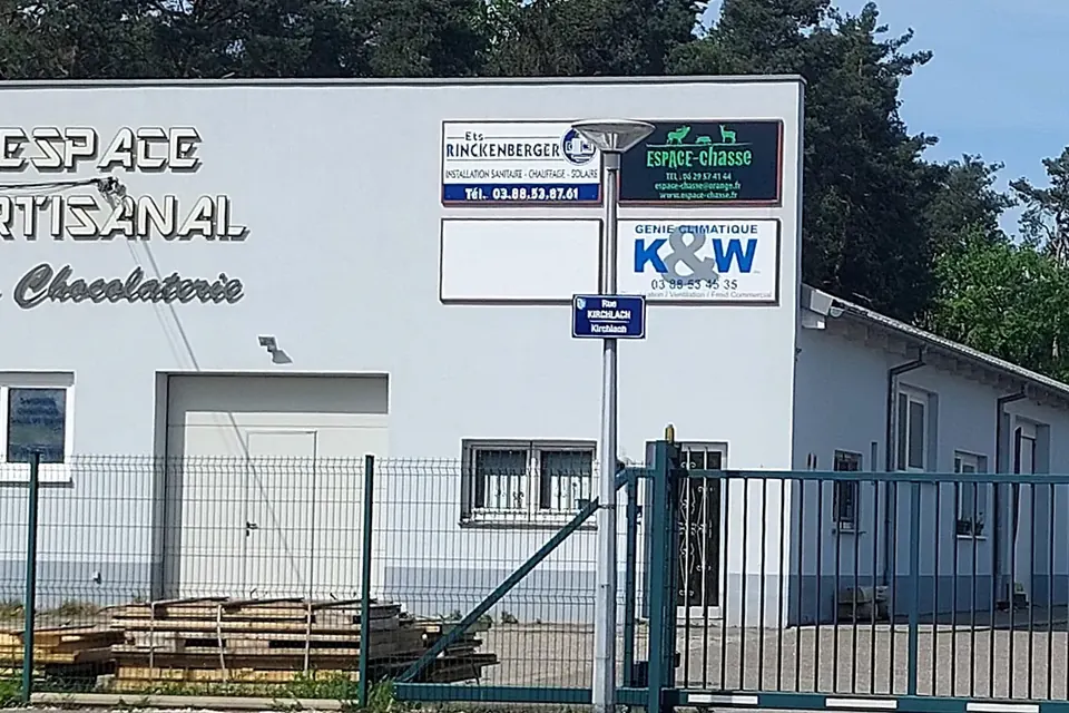 Bâtiment d'activités bas abritant plusieurs entreprises artisanales, sous un ciel bleu
