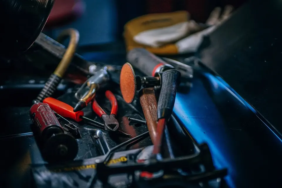 Bac à outils rempli de pinces, tournevis et clés dans un atelier sombre