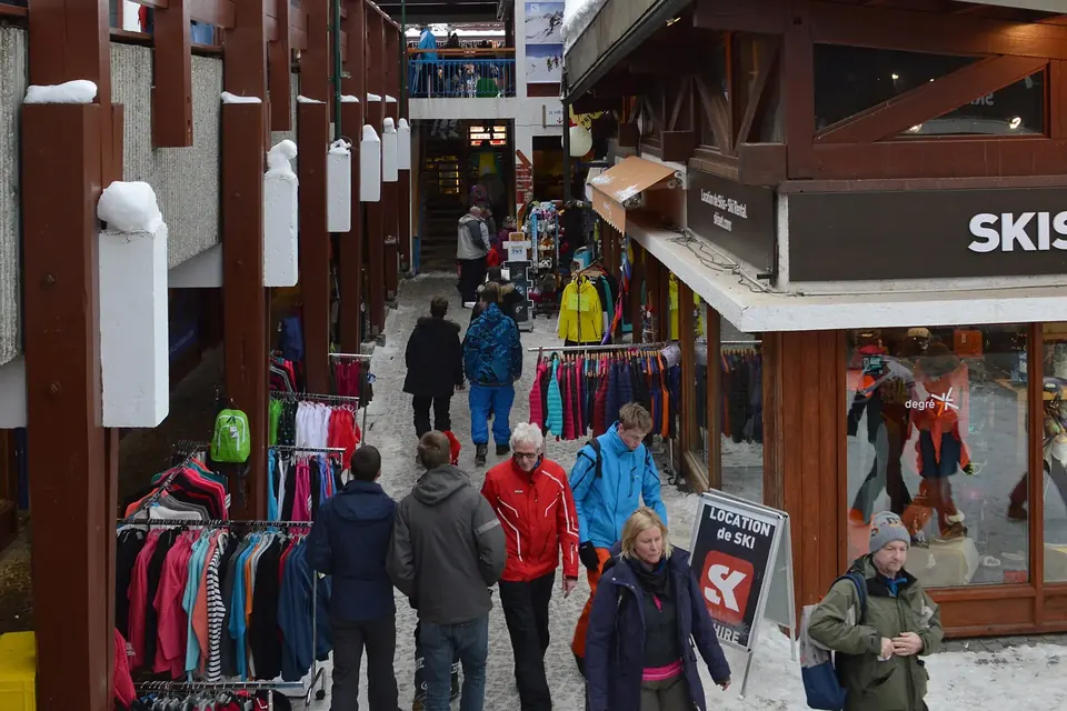 Rue commerçante piétonne d'une station de montagne, bordée de boutiques en bois, avec des passants